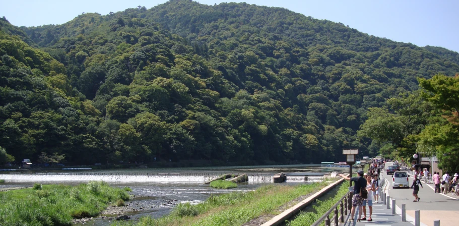 people are walking along the edge of a river