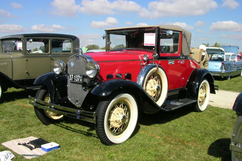 two old model cars sitting on top of the grass