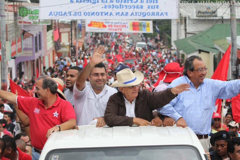 people sitting in the back of a car waving to the crowd