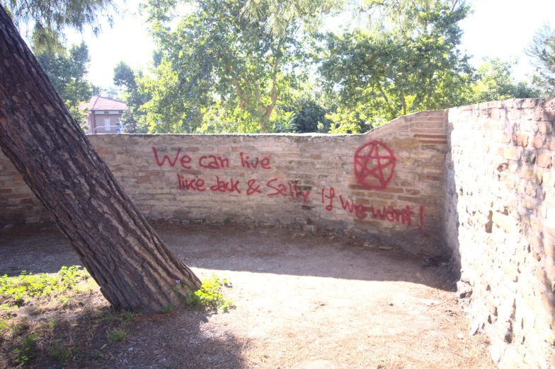 graffiti is shown on the wall next to a tree