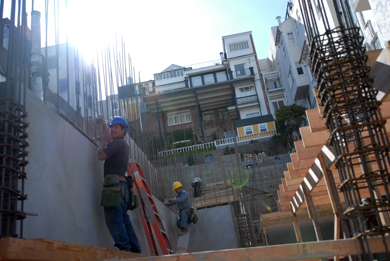 a construction worker stands on a staircase while another man checks out some type of structure