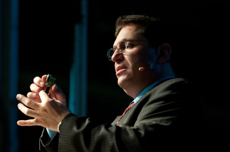 a man wearing a suit and tie, holds his hand out