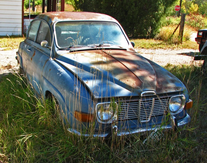 an old car is in the tall grass