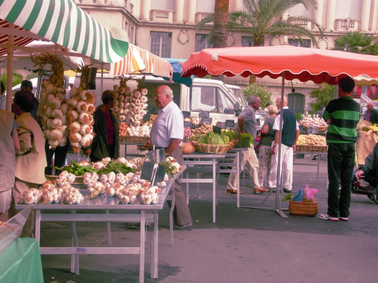 the men are at an open market selling vegetables