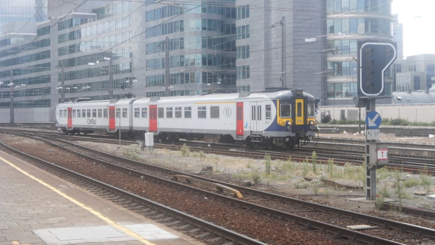 a long train traveling down the tracks next to some tall buildings