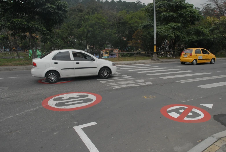 two white cars are on the street and one is yellow