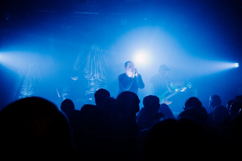 a band performs on stage with lights streaming down