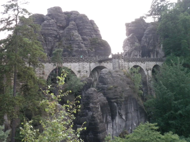 large rock formations with bridges over them on the side of a river