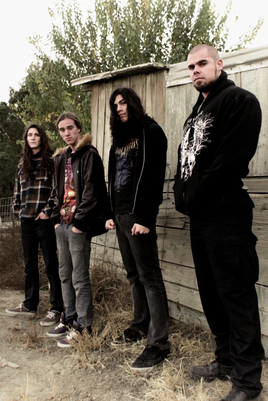 four people are standing in the grass next to a building