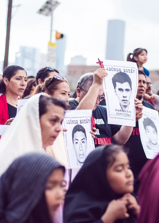 many people holding placares protesting with images of the same man