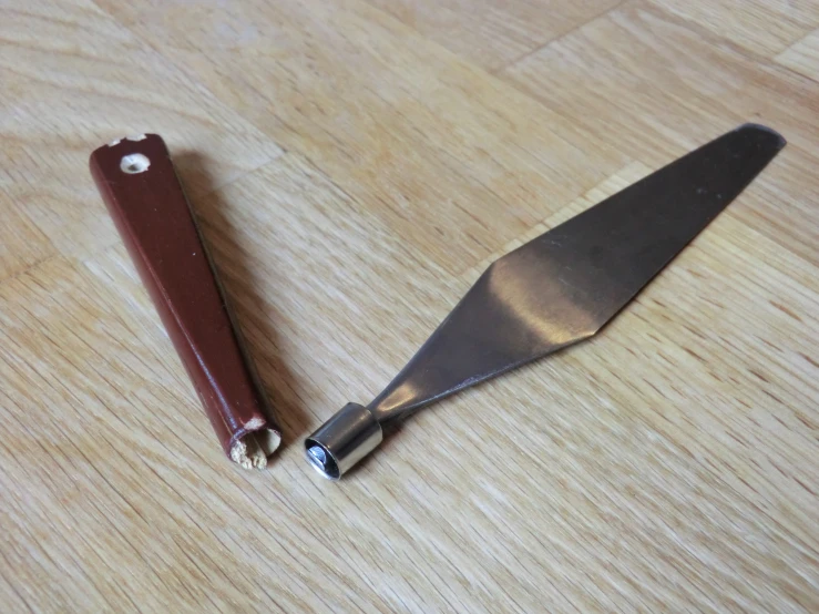 a large knife that is next to a knife blade on a table