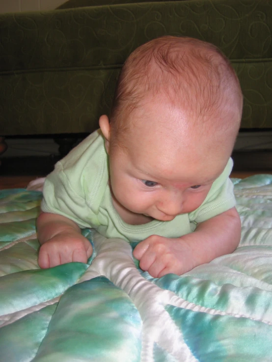 baby laying on blanket looking down at himself