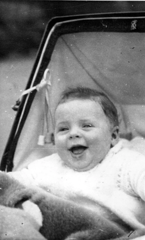 a baby in a car seat smiling for the camera