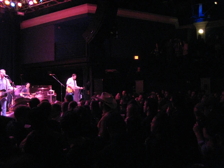 a band on stage playing music with people in the background