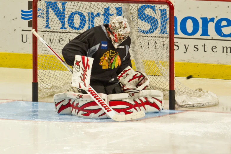 hockey goalie sitting next to net looking at soing