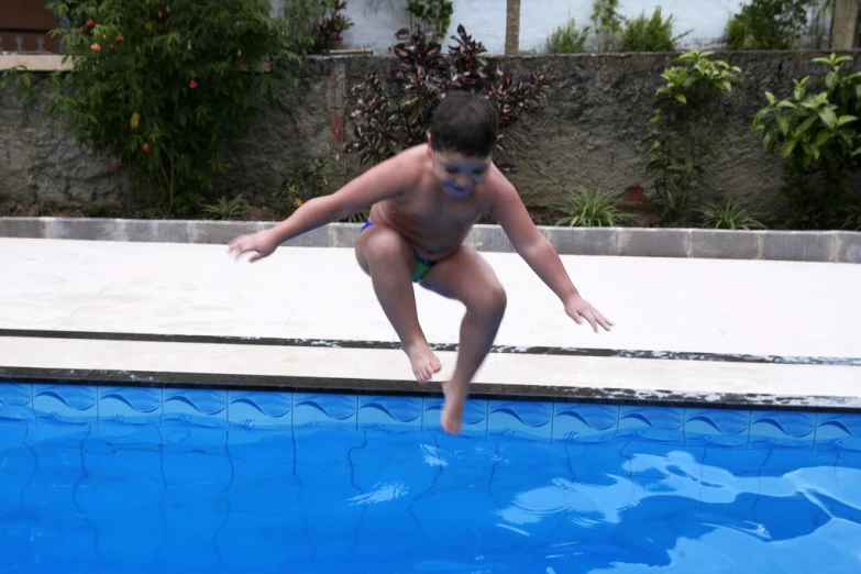 a child in a swimsuit jumping into the swimming pool