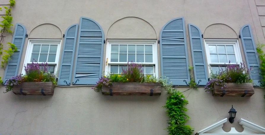 a building with blue shutters on the windows, filled with flower boxes