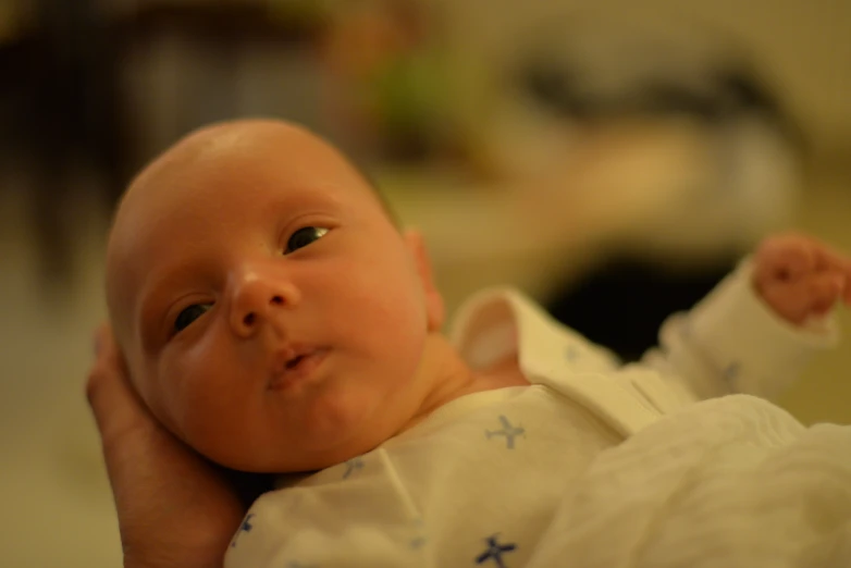 a close up of a baby holding the arm of someone