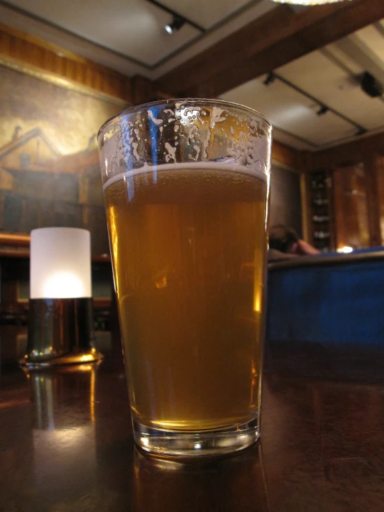 a glass of liquid sitting on a table in a restaurant