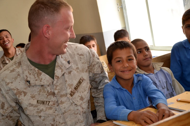 military man showing children how to use a computer