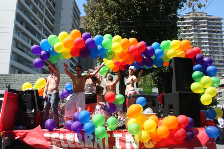 some people are standing behind a truck filled with balloons