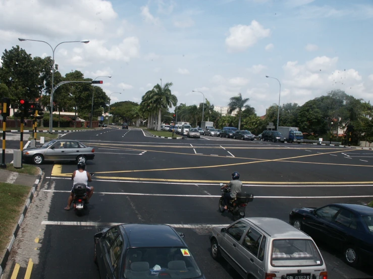 people on motorbikes drive past cars on the street