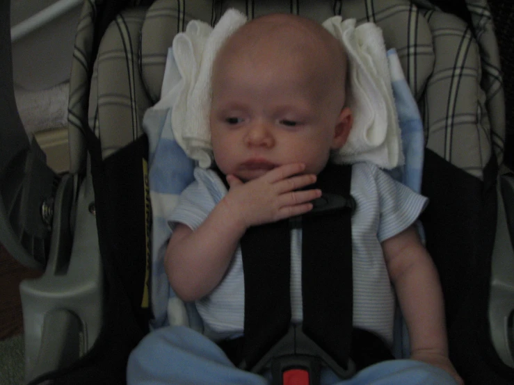 a baby who is holding his face in his seat