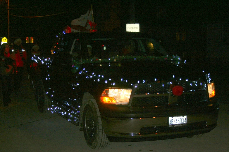 a car parked in front of a christmas tree that is lights on