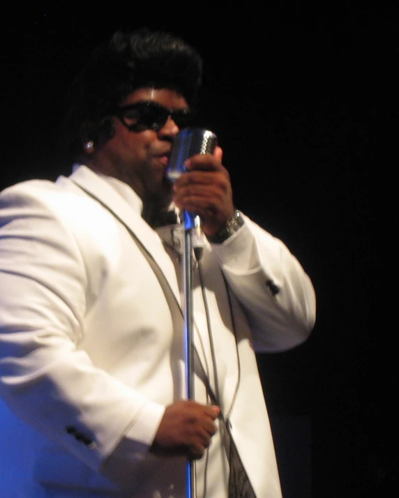 a man in a white suit holding a microphone