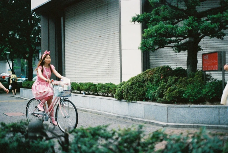 a woman on a bike with pink clothes and a hat