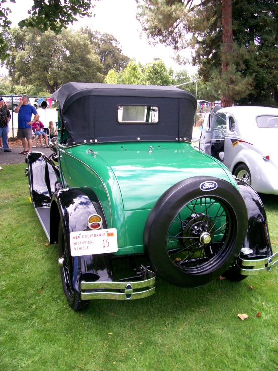 an old green car that is parked on the grass