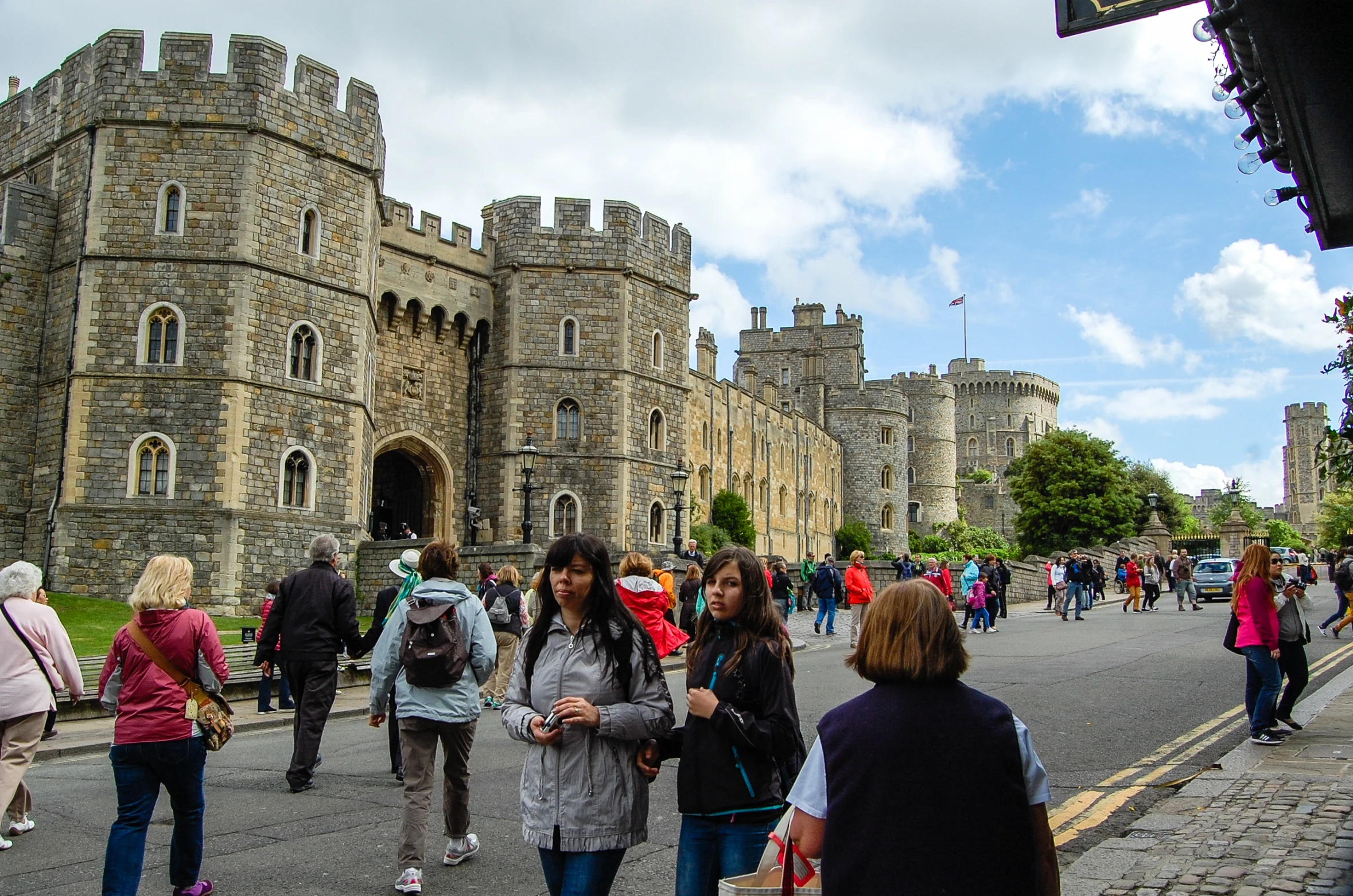 a crowd of people walking on the road near a castle