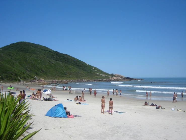 people in the sand near an island and a blue tent