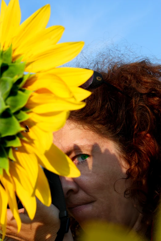 a woman wearing sunglasses holding a yellow sunflower