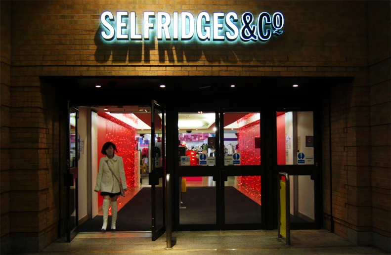 a woman standing in front of a red brick store entrance