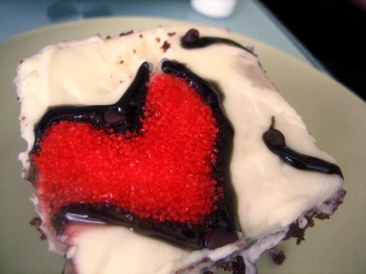 a close up of a piece of cake with white frosting and red icing