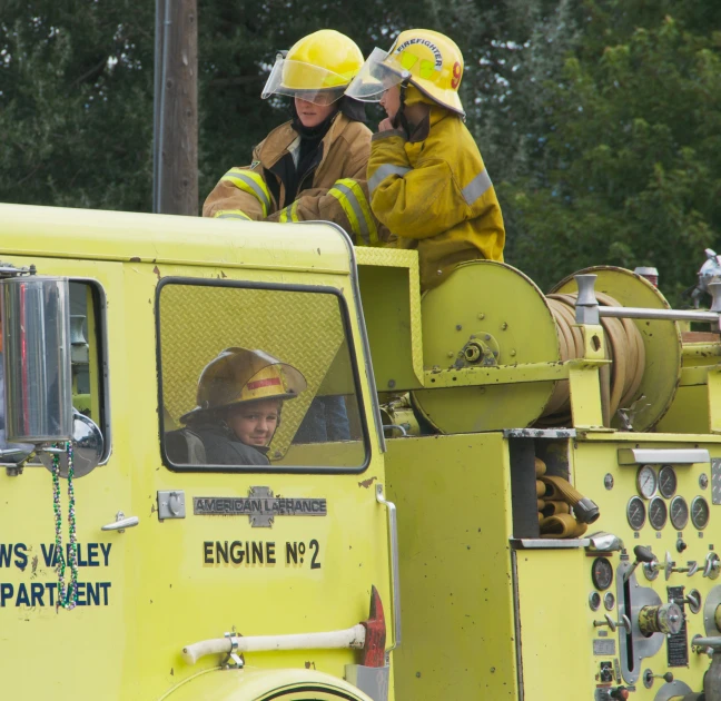 two firemen are sitting in the back of a truck