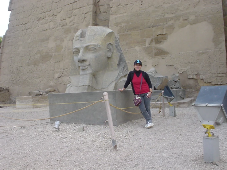 a woman standing in front of a huge stone egyptian head