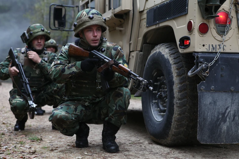 two military personnel with guns in their hand are crouching