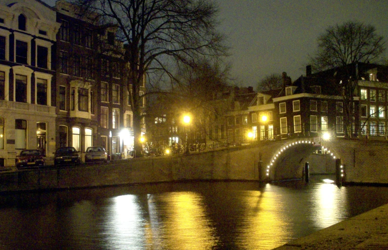 a bridge with lights and buildings by the water