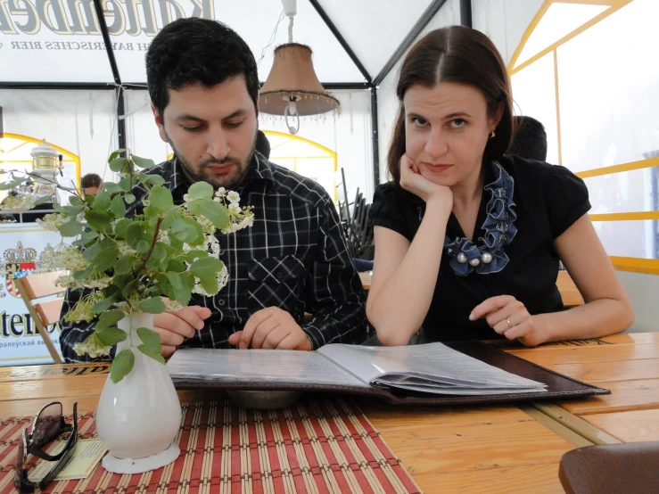 a man and woman are at a table with a magazine