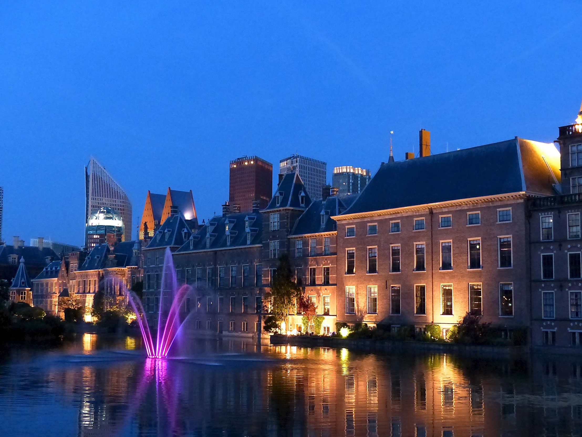 an urban skyline reflected in a lake at dusk