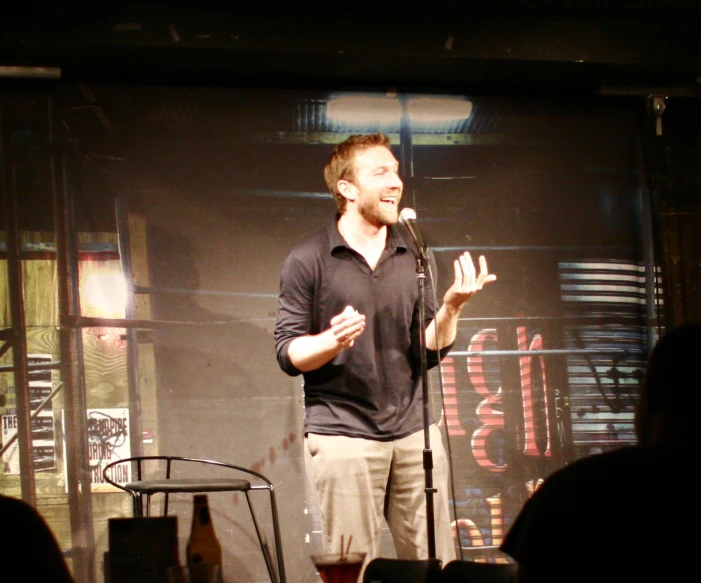 man in black shirt on stage speaking at a public event