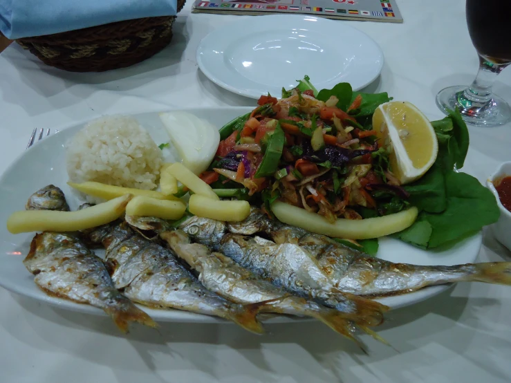 fish on a white plate with various vegetables and rice