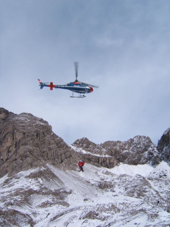 a large helicopter is in the air over a mountain