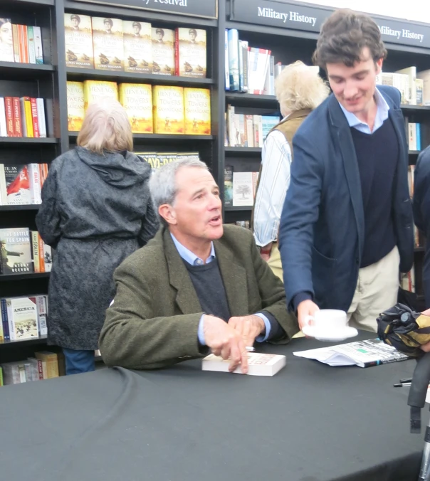 a man is signing autographs for two men