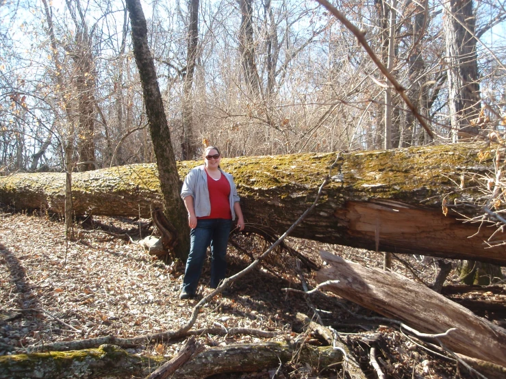 a man stands near trees in the woods