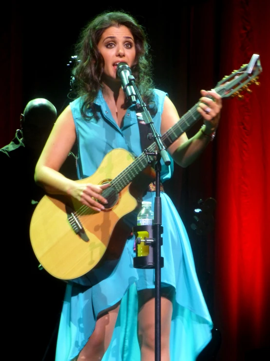 a woman playing an acoustic guitar on stage