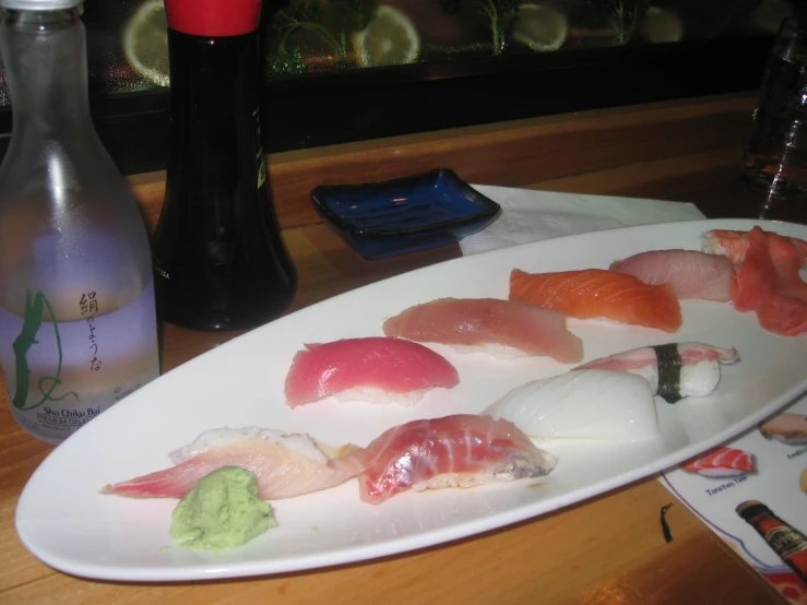 the sushi is laying on the plate near two empty soda bottles