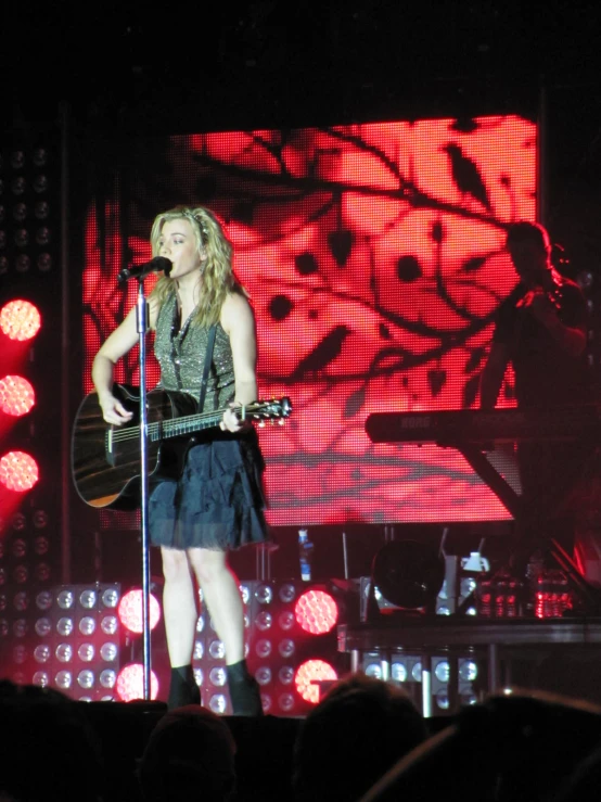 a person on stage with a guitar and microphone